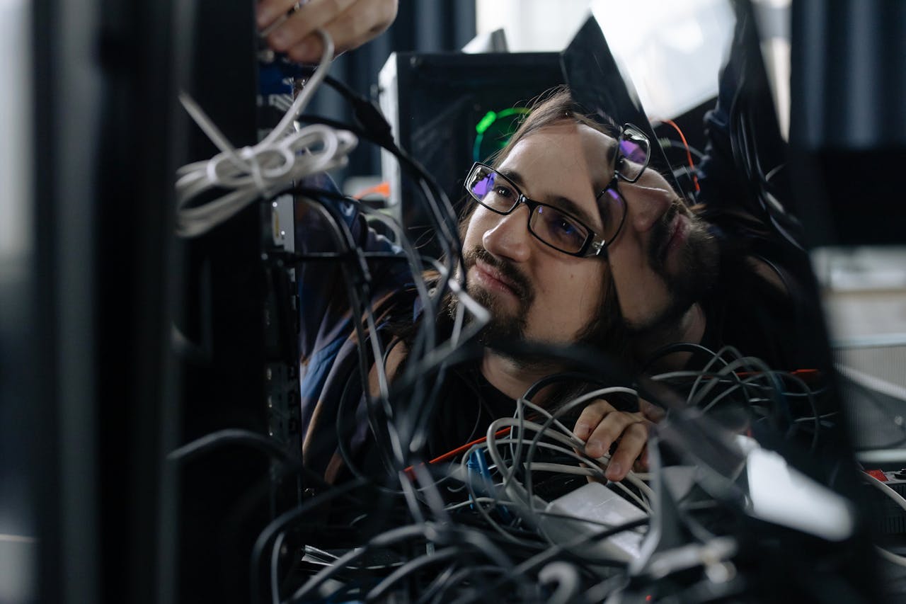 portfolio-03 A skilled IT technician organizing tangled cables at his workstation in an office environment.